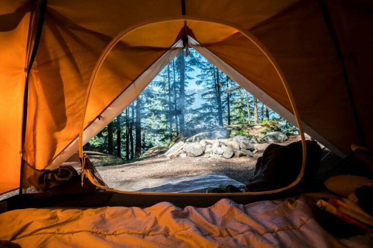 Tent glowing beside a campfire at dusk in the mountains