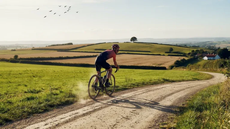 A cyclist riding a gravel bike on a country road at golden hour
