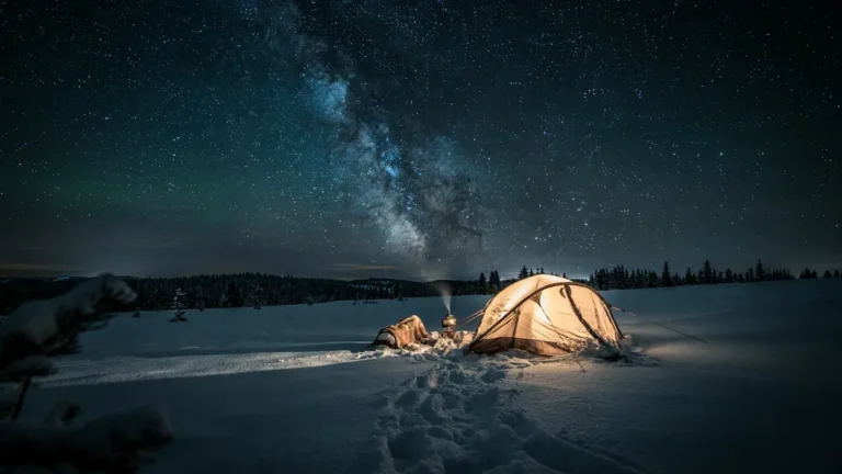 Glowing tent on snow under a starry winter sky