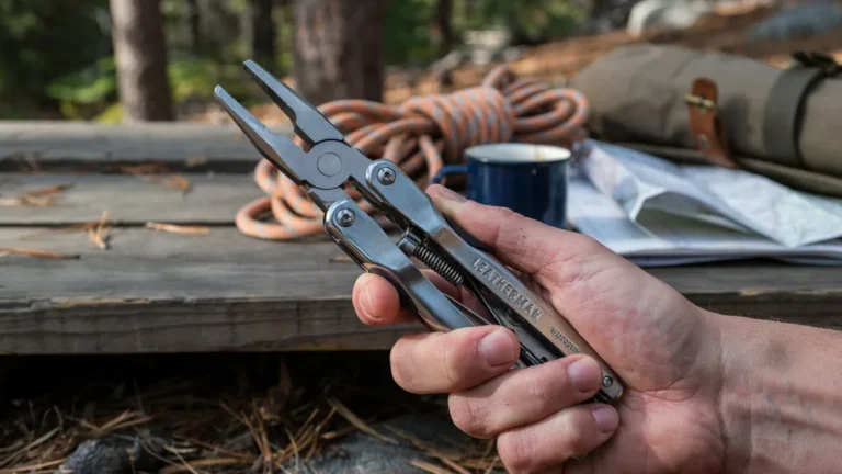Multi-tool with pliers extended held over camping gear
