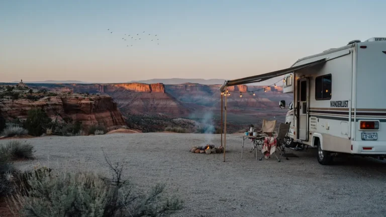 RV parked at a scenic campsite overlooking red rock mesas at sunset