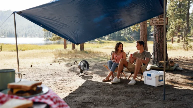Shaded summer campsite with canopy, fan, and cold drinks